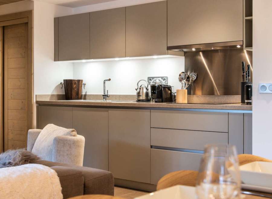 This stunning kitchen boasts sleek, modern cabinetry in a sophisticated taupe shade, complemented by brushed stainless steel appliances and countertops.