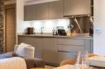 This stunning kitchen boasts sleek, modern cabinetry in a sophisticated taupe shade, complemented by brushed stainless steel appliances and countertops.