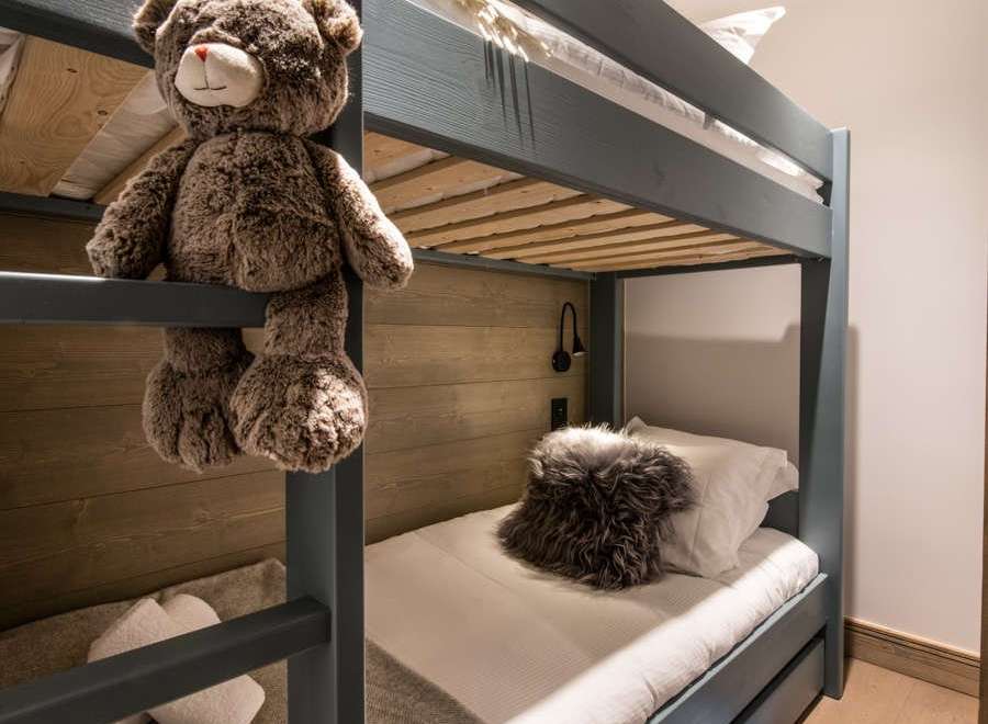 Cozy bunk beds with plush teddy bear and soft blankets create a warm and inviting atmosphere for children.