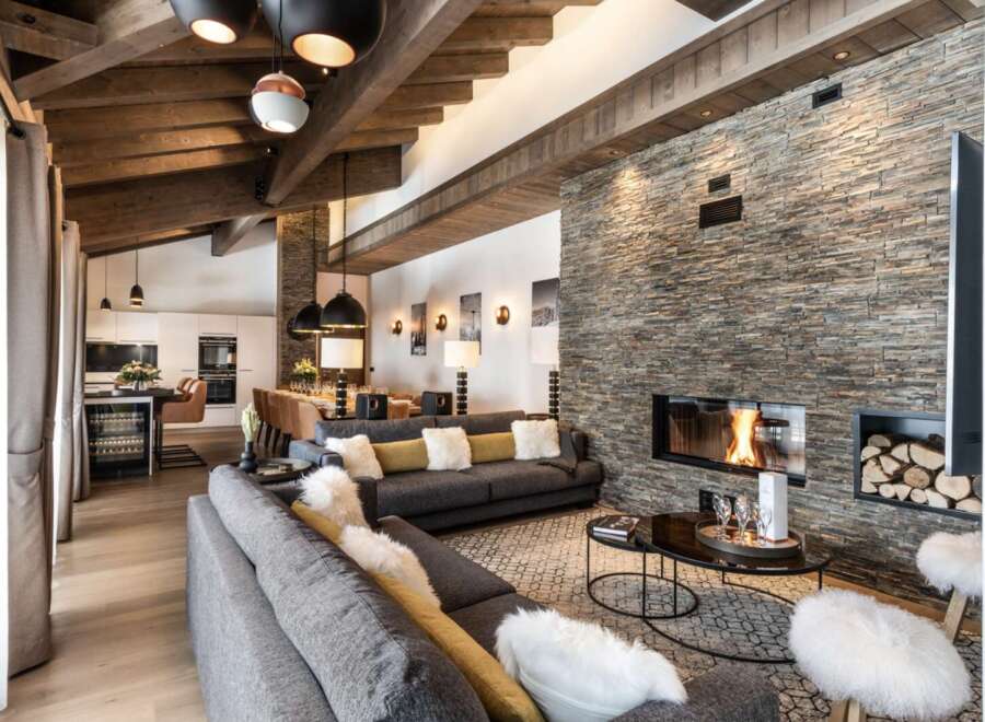 This luxurious chalet boasts a spacious open-plan living area with a stunning stone fireplace, perfect for cozy nights in.