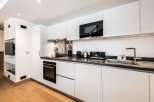 Modern kitchen with white cabinets, dark countertops, and integrated appliances including a microwave, oven, and cooktop.