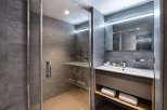 Modern bathroom with a walk-in shower, sleek gray tile, and a floating vanity with integrated shelving.