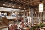 This luxurious chalet boasts a stunning dining area with a rustic-chic design, featuring a long wooden table adorned with candles and greenery, surrounded by cowhide chairs.