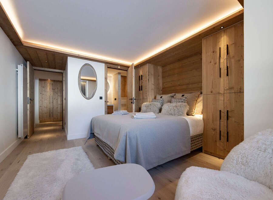 Experience luxury in this stunning bedroom featuring a cozy bed, plush pillows, and elegant wooden accents.