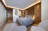 Experience luxury in this stunning bedroom featuring a cozy bed, plush pillows, and elegant wooden accents.