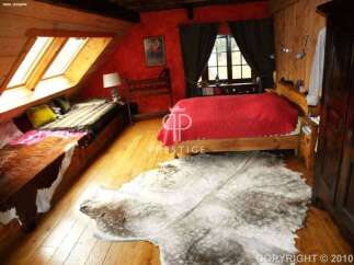 This cozy bedroom features a unique design with wooden accents and a vibrant red wall.