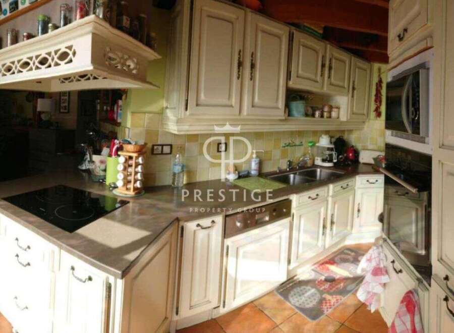 Discover a charming kitchen with classic cabinetry and a sleek cooktop, perfect for culinary enthusiasts.