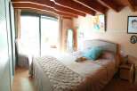 Cozy bedroom with a rustic touch, featuring exposed wooden beams and a comfortable bed.