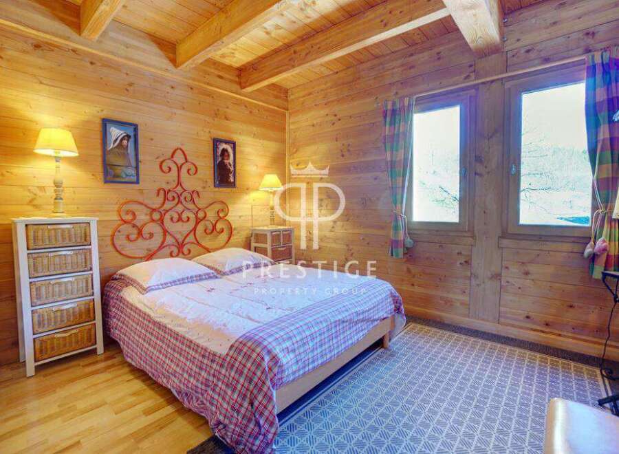 Cozy bedroom with wooden walls and ceiling, creating a warm and inviting atmosphere.