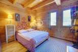 Cozy bedroom with wooden walls and ceiling, creating a warm and inviting atmosphere.