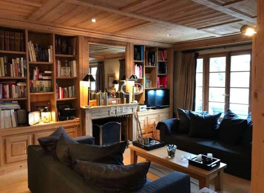 Step into a cozy living room with a rustic charm, featuring a stunning wooden ceiling and built-in bookshelves.