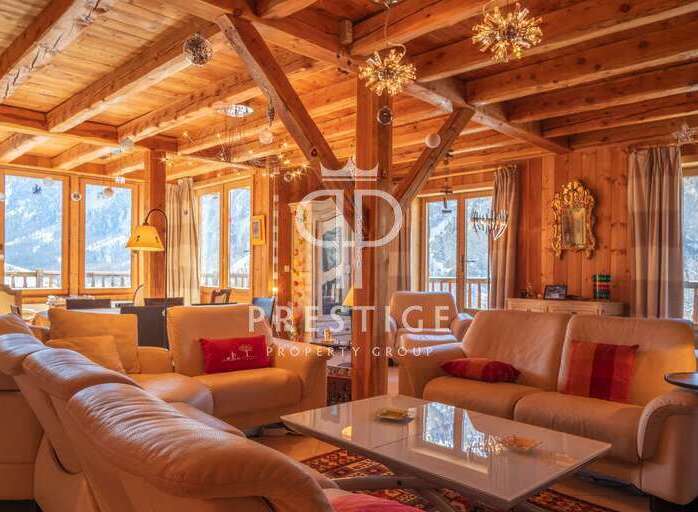 Experience luxury living in this stunning chalet, featuring a warm and inviting interior with exposed wooden beams.