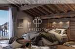 Experience luxury living in this stunning chalet, featuring a cozy bedroom with a rustic wooden ceiling and walls.