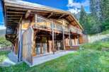 Discover a stunning wooden chalet nestled in a picturesque mountain setting.