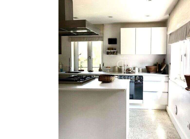 This modern kitchen boasts sleek white cabinetry and countertops, creating a bright and airy atmosphere.