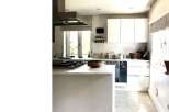 This modern kitchen boasts sleek white cabinetry and countertops, creating a bright and airy atmosphere.