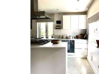 This modern kitchen boasts sleek white cabinetry and countertops, creating a bright and airy atmosphere.