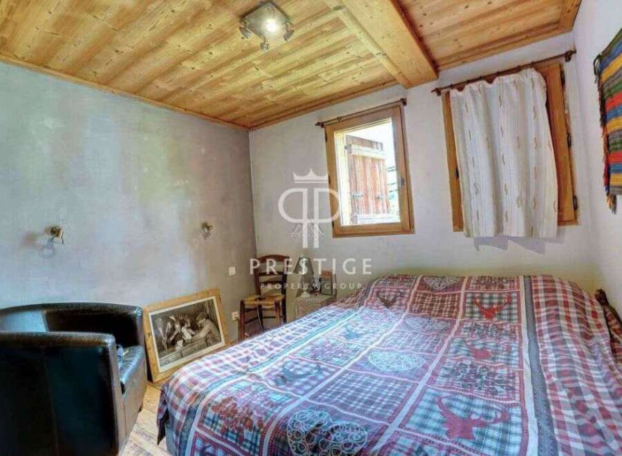 Discover the charm of this cozy bedroom, featuring a rustic wooden ceiling and a comfortable bed with a unique patterned quilt.