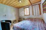 Discover the charm of this cozy bedroom, featuring a rustic wooden ceiling and a comfortable bed with a unique patterned quilt.