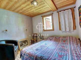 Discover the charm of this cozy bedroom, featuring a rustic wooden ceiling and a comfortable bed with a unique patterned quilt.