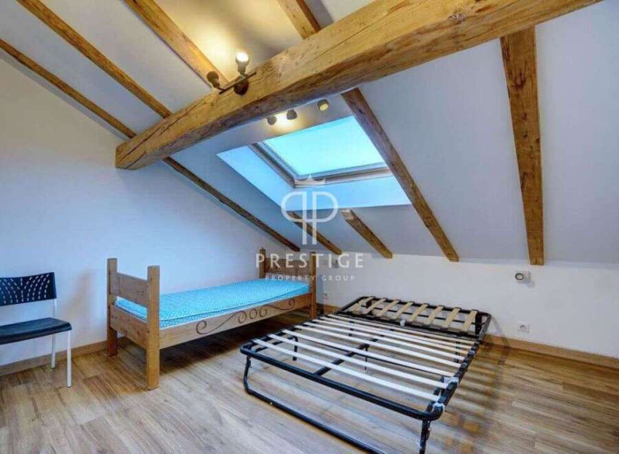Discover a charming attic bedroom with exposed wooden beams, creating a cozy and inviting atmosphere.