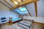Discover a charming attic bedroom with exposed wooden beams, creating a cozy and inviting atmosphere.