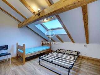 Discover a charming attic bedroom with exposed wooden beams, creating a cozy and inviting atmosphere.