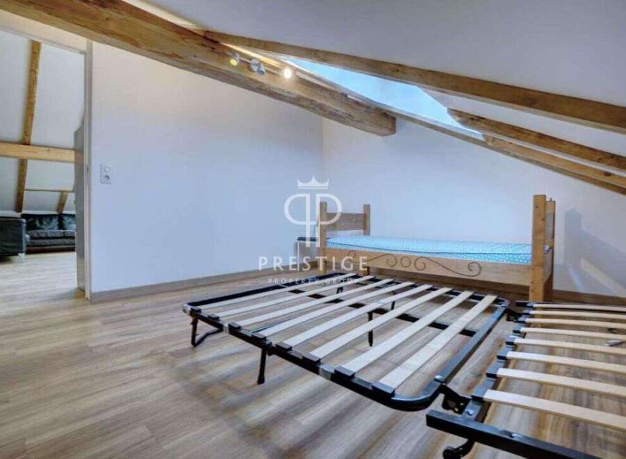 Discover this charming property featuring a cozy bedroom with exposed wooden beams, creating a warm and inviting atmosphere.