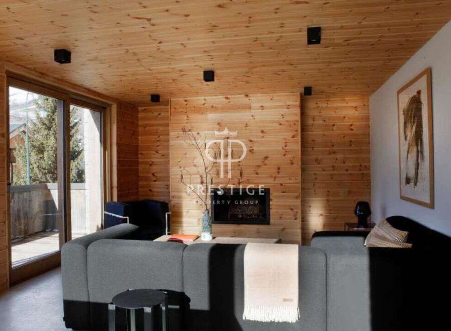 Experience luxury living in this stunning property, featuring a cozy living room with a fireplace and wooden accents.