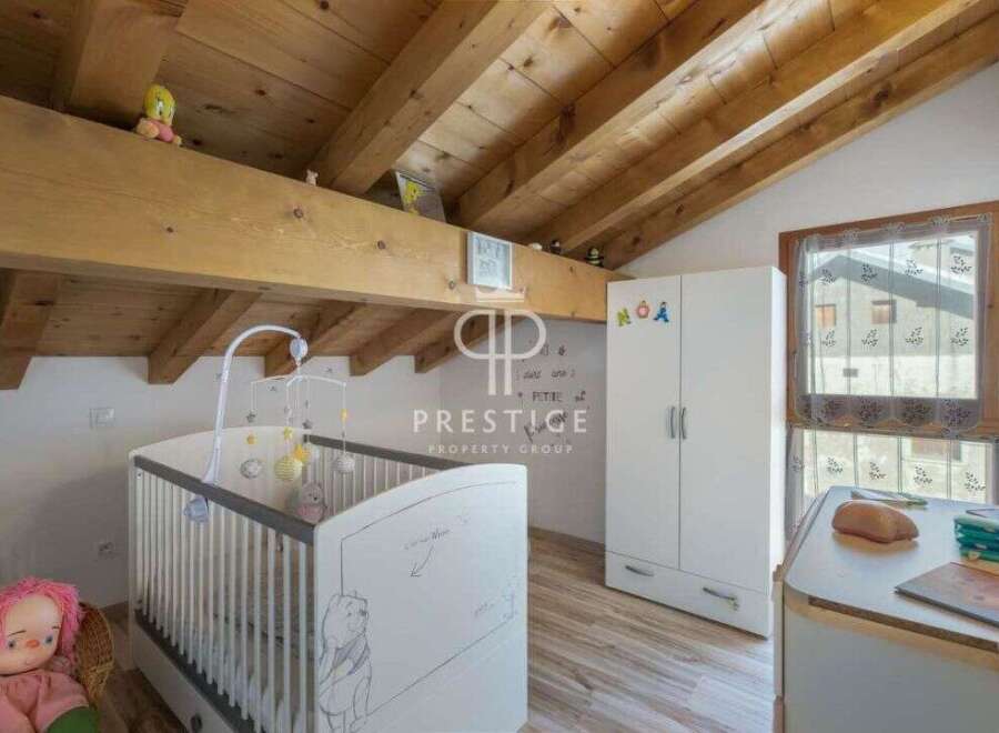 Discover a charming nursery with a cozy, wooden-beamed ceiling.