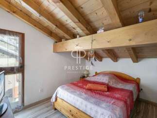 Discover a cozy bedroom with a rustic wooden ceiling and beams, creating a warm and inviting atmosphere.
