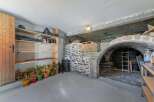 Discover the charm of this unique property, featuring a rustic stone archway and a spacious storage area.