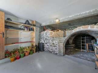 Discover the charm of this unique property, featuring a rustic stone archway and a spacious storage area.