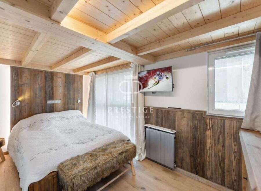 Experience rustic charm in this cozy bedroom featuring a wooden ceiling and walls, creating a warm and inviting atmosphere.