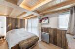 Experience rustic charm in this cozy bedroom featuring a wooden ceiling and walls, creating a warm and inviting atmosphere.