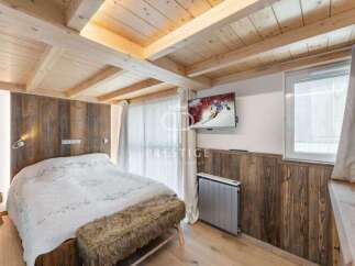 Experience rustic charm in this cozy bedroom featuring a wooden ceiling and walls, creating a warm and inviting atmosphere.