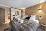 Experience luxury in this stunning bedroom featuring a cozy fur blanket and elegant wooden accents.