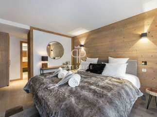 Experience luxury in this stunning bedroom featuring a cozy fur blanket and elegant wooden accents.