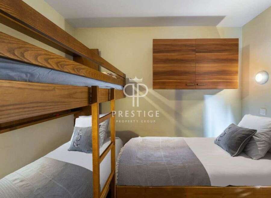 Discover a cozy bedroom featuring a stylish bunk bed and a comfortable single bed, perfect for accommodating guests.