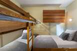 Discover a cozy bedroom featuring a stylish bunk bed and a comfortable single bed, perfect for accommodating guests.