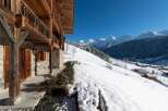 Experience the charm of a traditional wooden chalet nestled in a snowy mountain landscape.