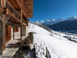 Experience the charm of a traditional wooden chalet nestled in a snowy mountain landscape.