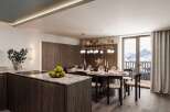 This stunning apartment boasts a modern kitchen with granite countertops and sleek cabinetry, seamlessly flowing into a dining area with a breathtaking mountain view.