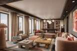 This luxurious living space boasts floor-to-ceiling windows offering breathtaking mountain views, complemented by a stylish and modern interior design.