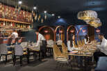 This stunning restaurant boasts a unique design, featuring a stylish bar with hanging bottle lights and a sophisticated dining area with a mix of modern and rustic chairs.