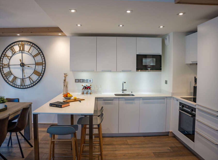 This stunning kitchen boasts modern white cabinetry, sleek countertops, and high-end appliances, creating a bright and airy atmosphere.