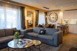 This stunning apartment boasts an open-plan living area with comfortable grey sofas, a stylish glass coffee table, and large windows offering ample natural light.