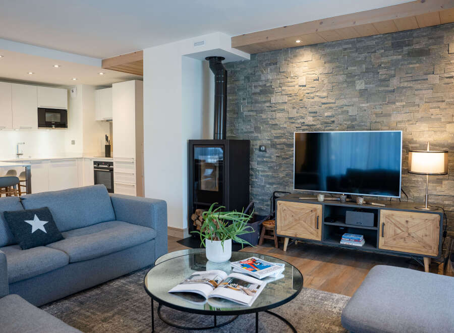 This stunning living room boasts a cozy fireplace, a large flat-screen TV, and comfortable gray sofas perfect for relaxing.