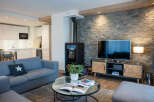 This stunning living room boasts a cozy fireplace, a large flat-screen TV, and comfortable gray sofas perfect for relaxing.