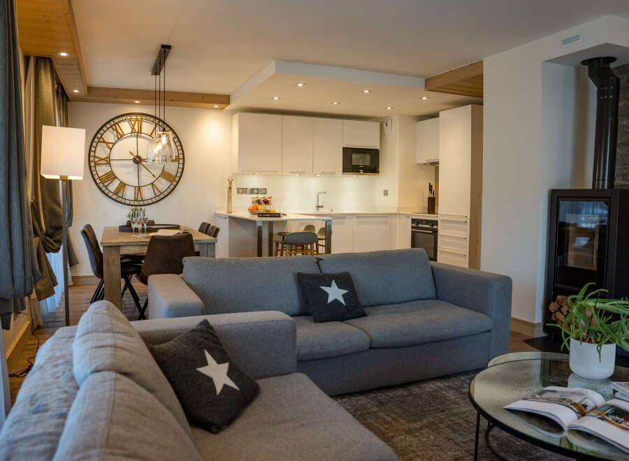 This stunning apartment boasts an open-plan living area with a cozy sofa and a modern kitchen, perfect for entertaining guests.